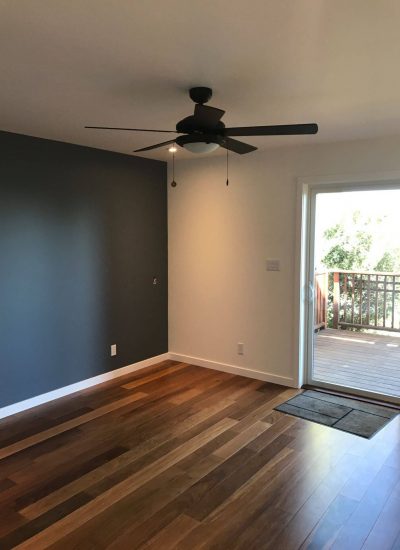 Navy blue wall and white wall with a new hardwood floor.